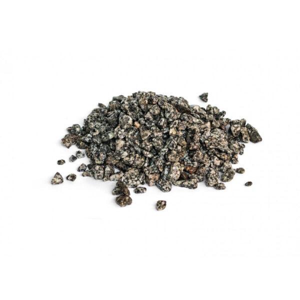 Ein kleiner Haufen grober, dunkler Körner mit einer rauen Textur, verstreut auf einem weißen Hintergrund.