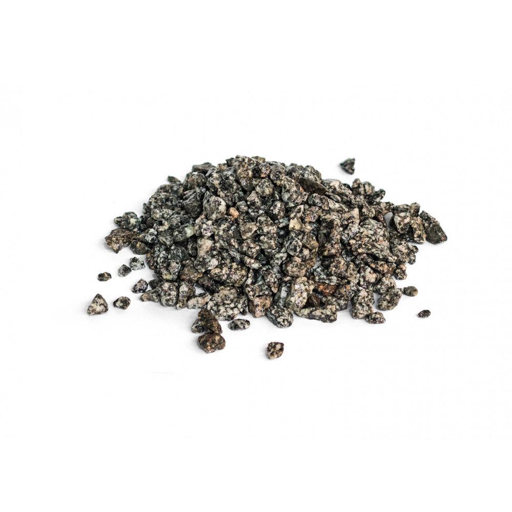 Ein kleiner Haufen grober, dunkler Körner mit einer rauen Textur, verstreut auf einem weißen Hintergrund.